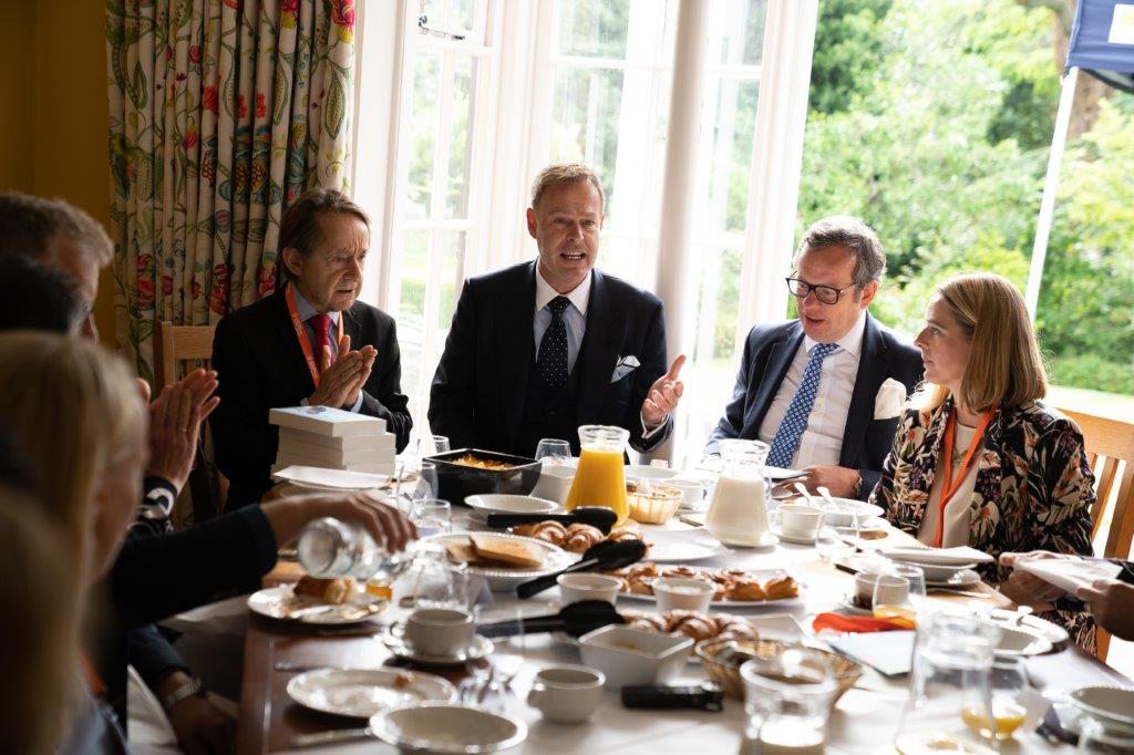Peter Jones talking with guests around a breakfast table at an enterprise event