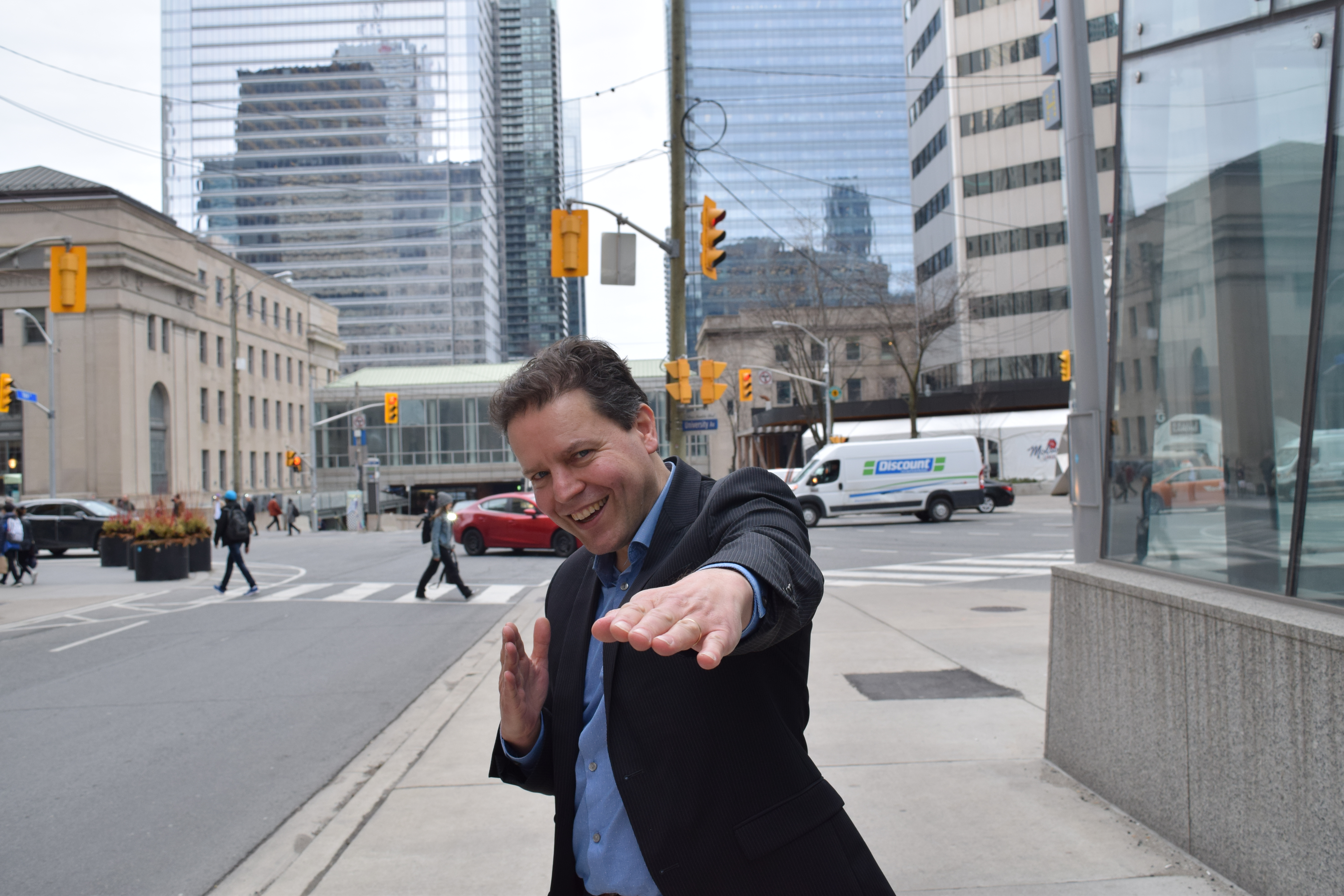 Peter-Paul Van Hoeken smiling and extending an arm on a downtown street