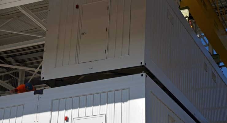 An overhead crane lowers a modular data center vault onto another at Keystone NAP
