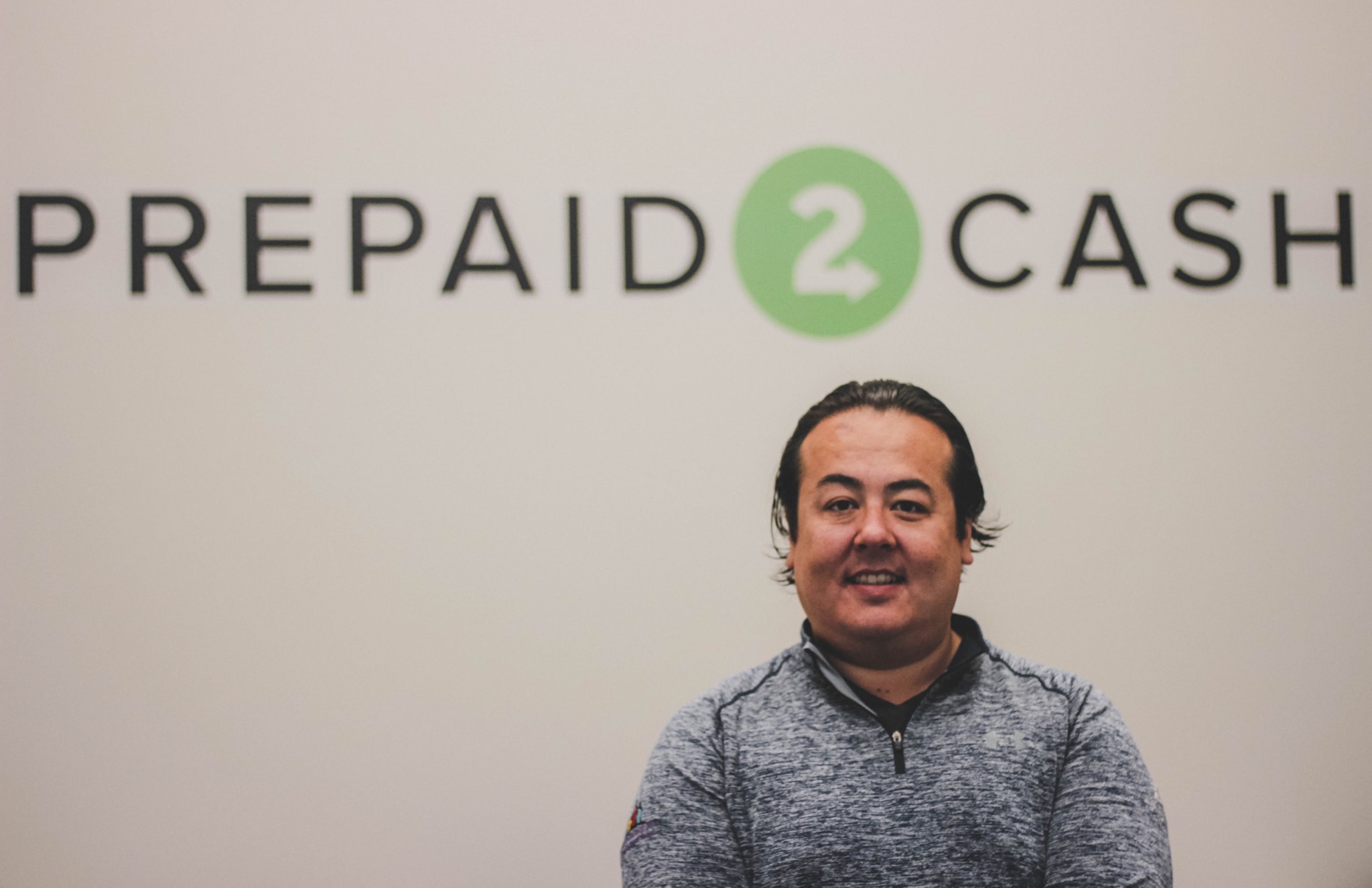 Peter Vogt seated beneath the Prepaid2Cash wordmark at the company's office