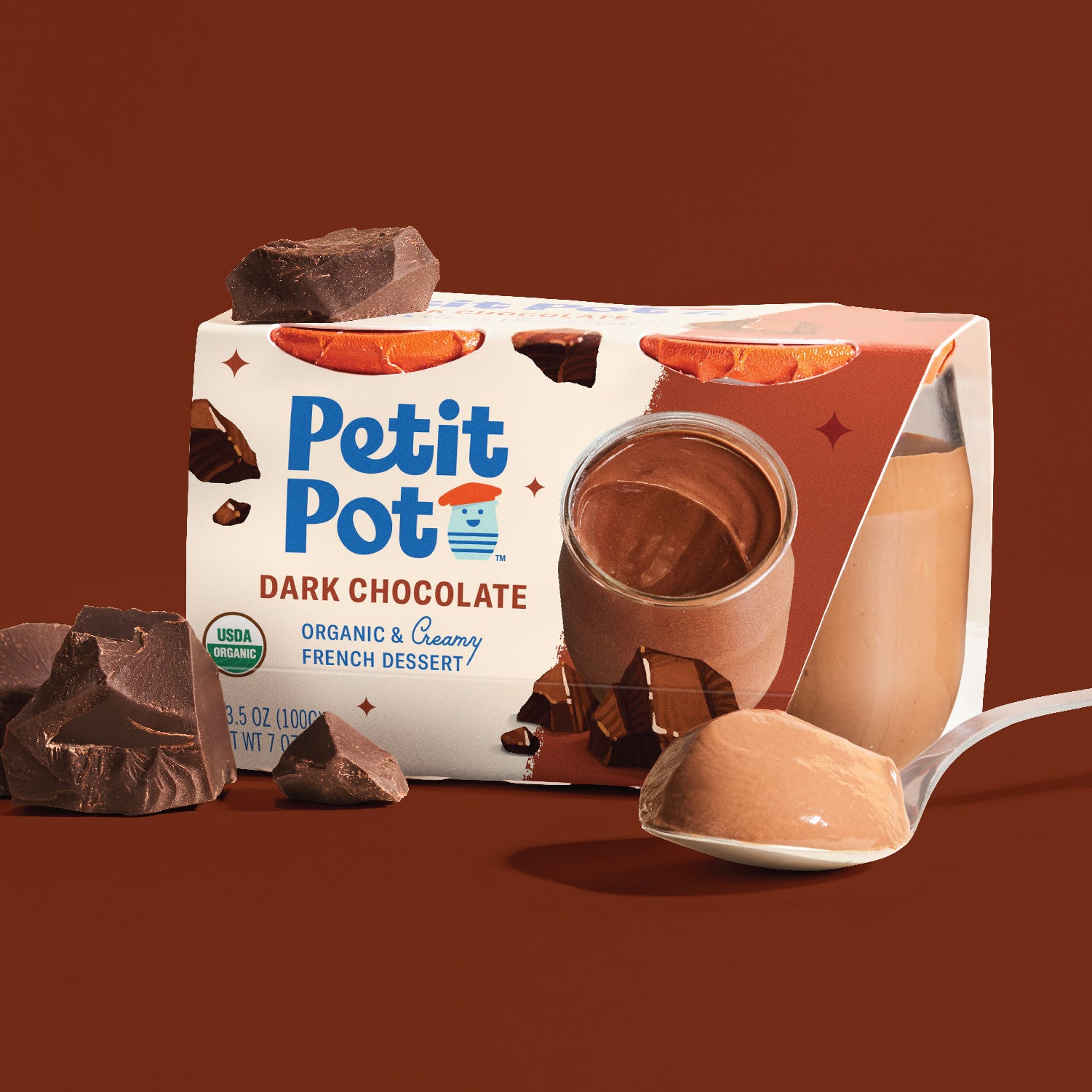Petit Pot dark chocolate dessert in a glass jar beside its two-pack carton, chocolate pieces and a spoon