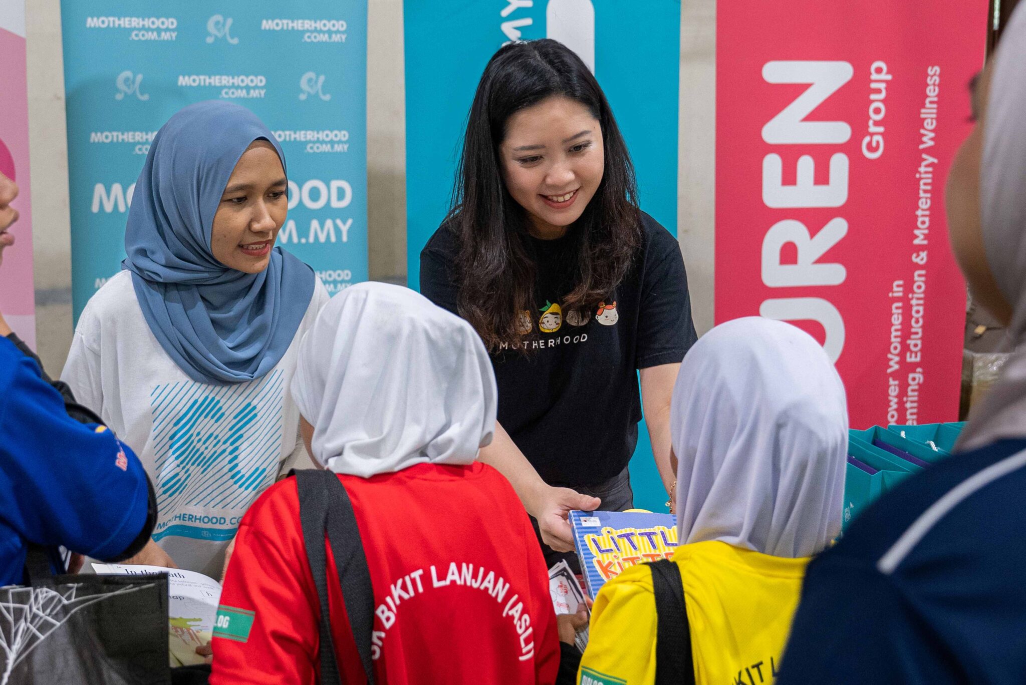 Petrina Goh, wearing a Motherhood T-shirt, sharing books with children at a community activity