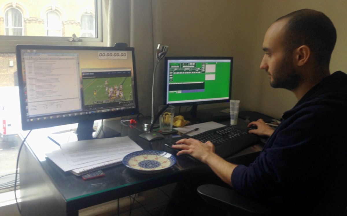 A PFF analyst studies game footage beside a second monitor of football data