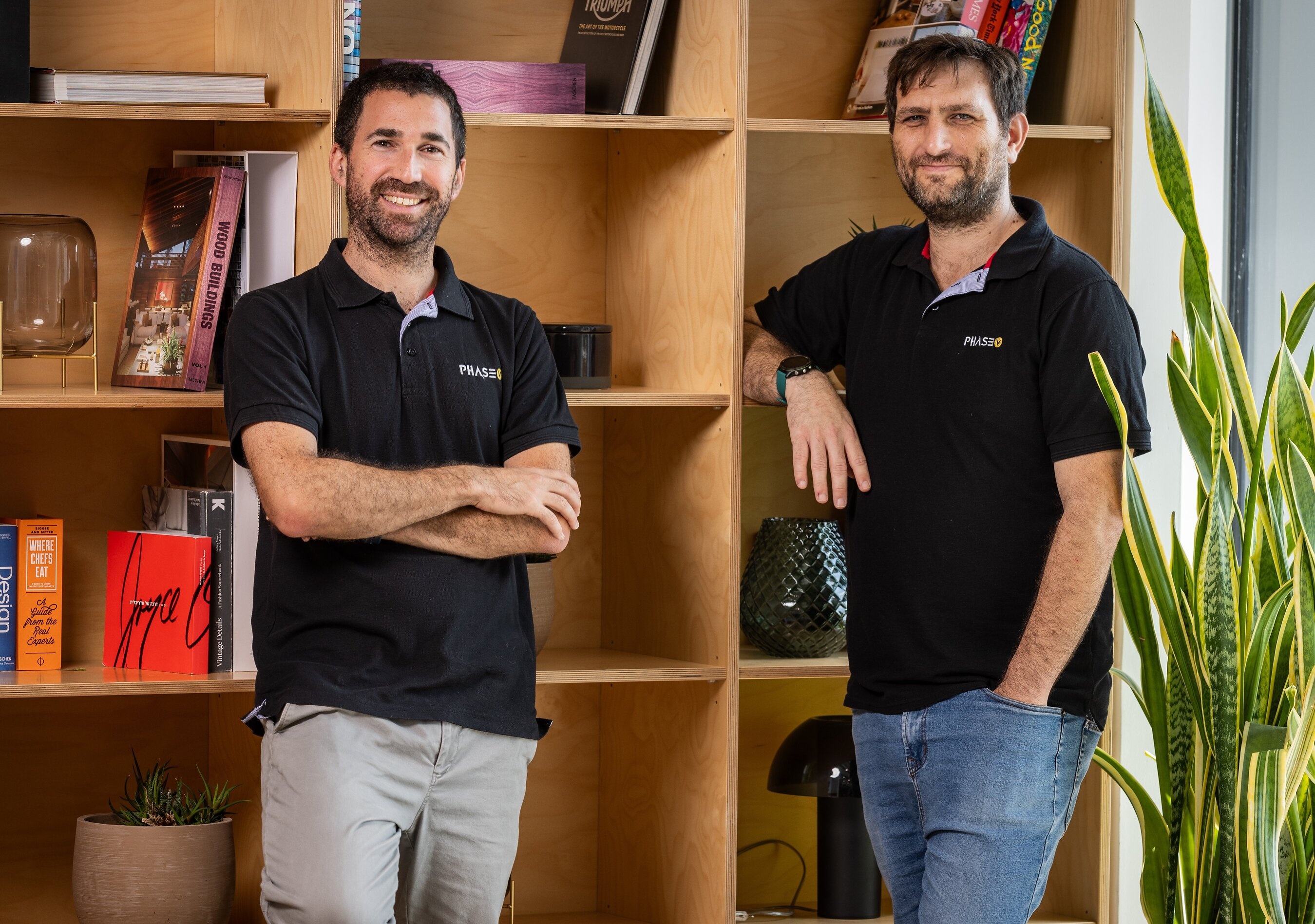 PhaseV co-founders Raviv Pryluk and Elad Berkman standing beside wooden bookshelves