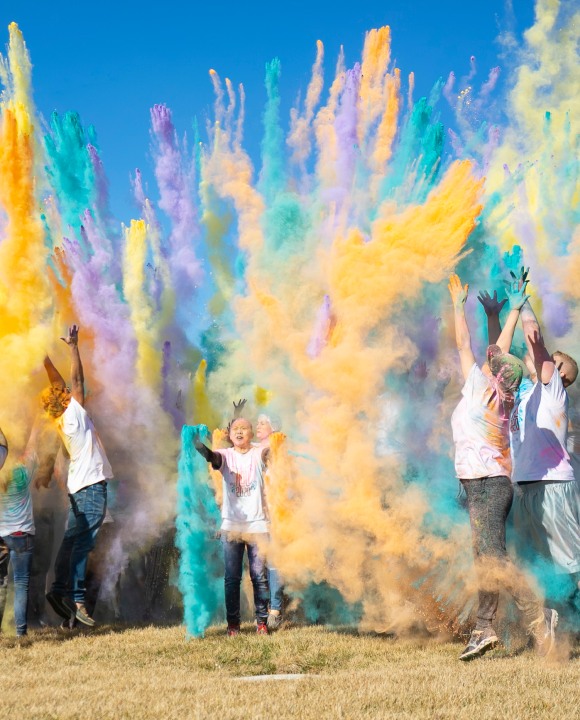 Phenom employees throw clouds of colored powder during a Holi celebration