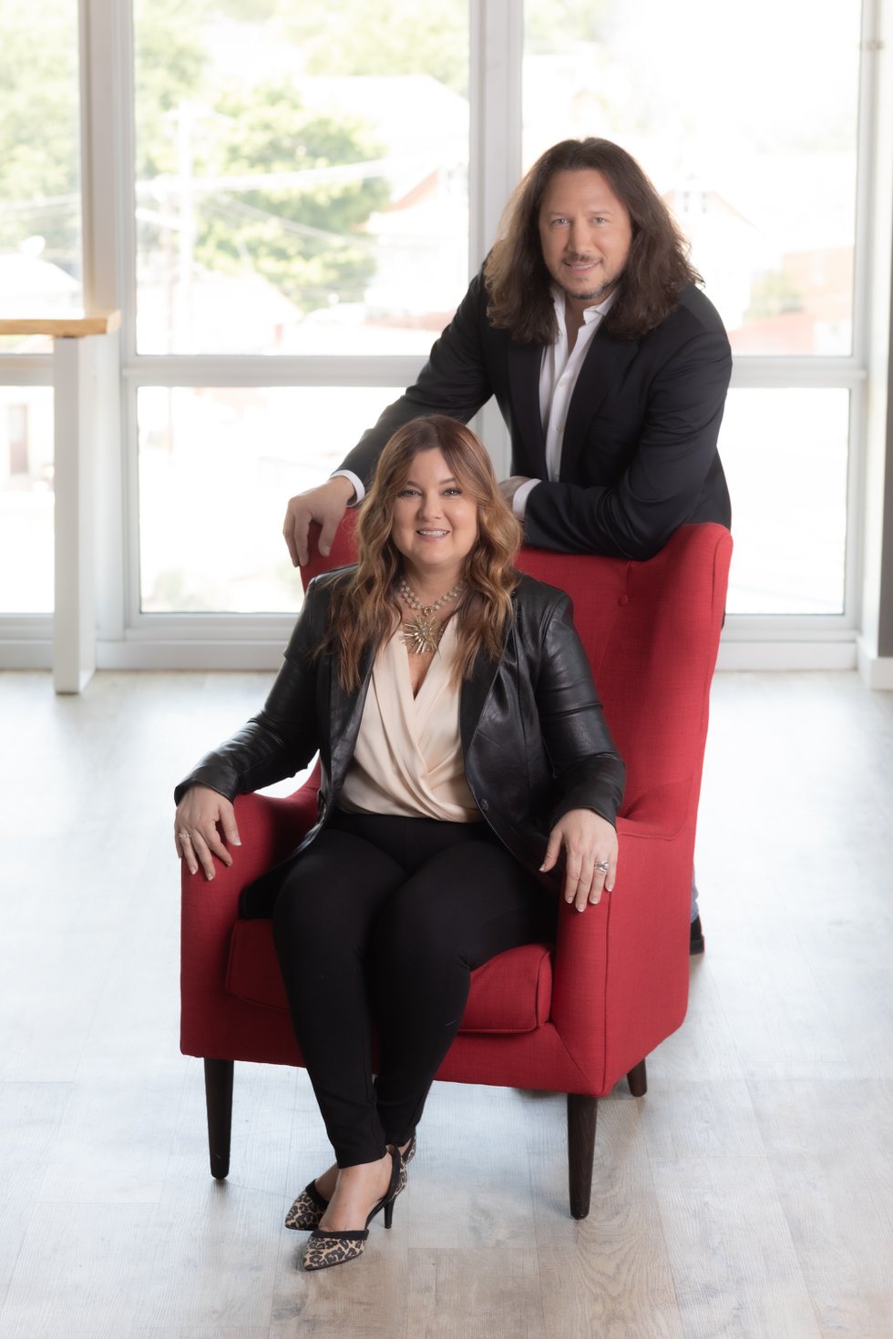 Tracy Landau seated in a red chair with Phil Landau standing behind her