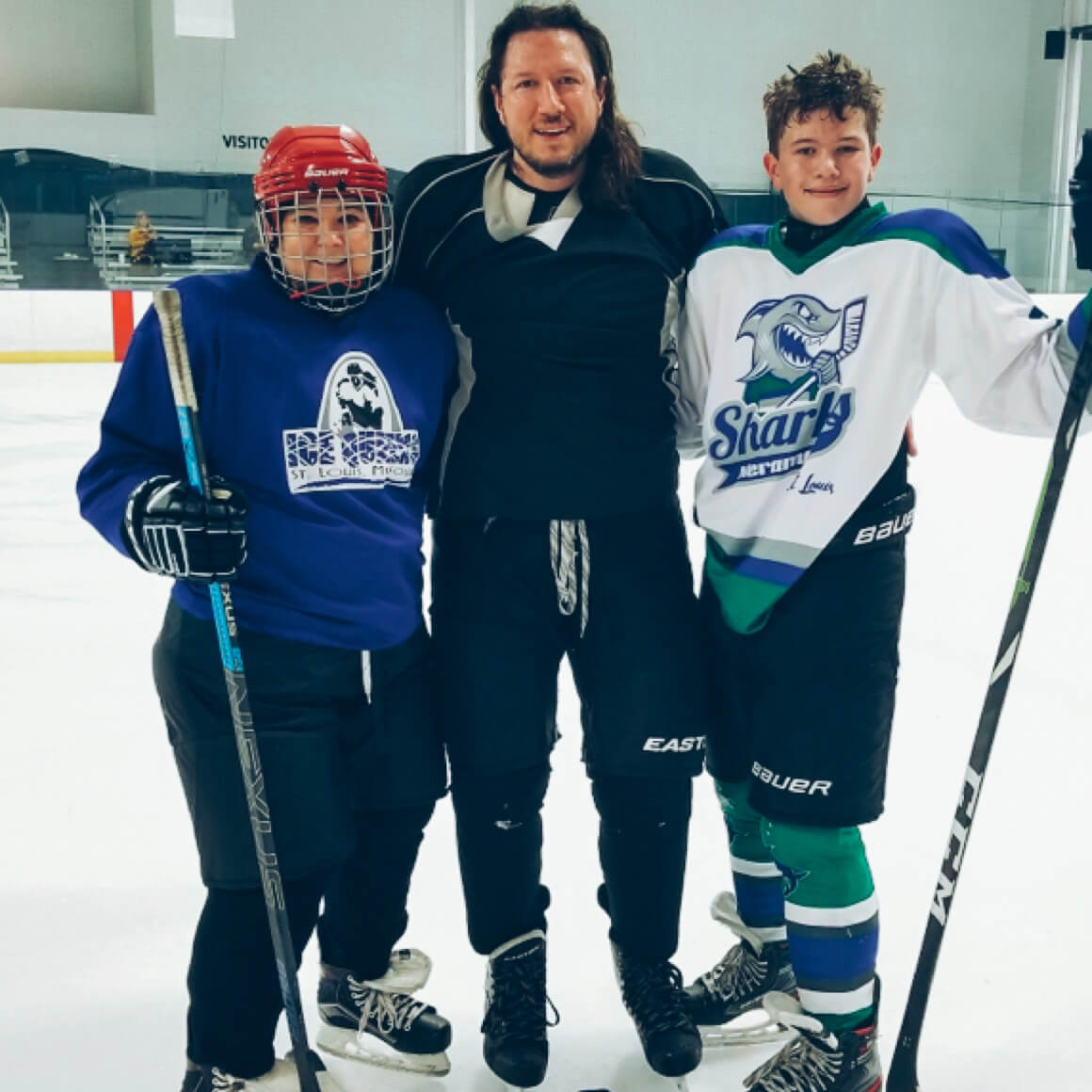 Phil Landau on an ice rink with two young hockey players in a family photograph