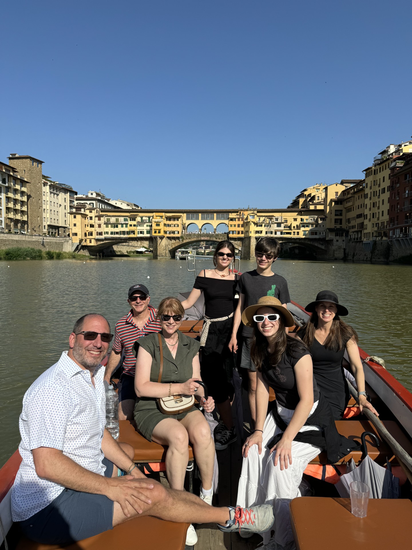 Philip Mekelburg, seated at front left, boating with a group on the Arno in Florence, with the Ponte Vecchio behind them