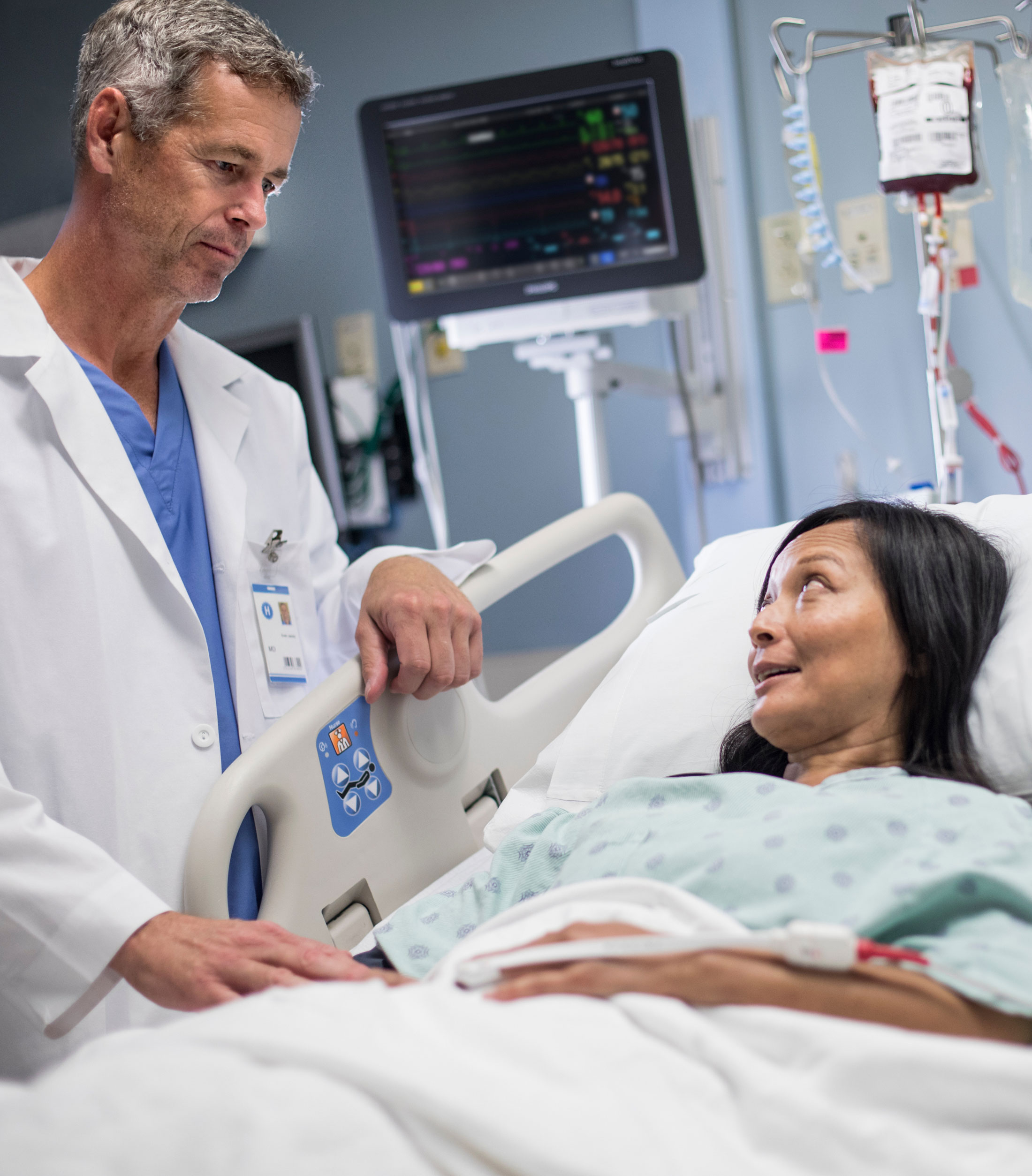 A clinician beside a patient, with bedside monitoring equipment behind them