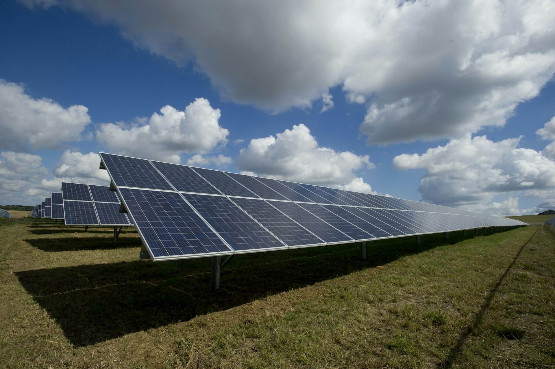 Rows of solar panels beneath a wide, cloud-filled sky