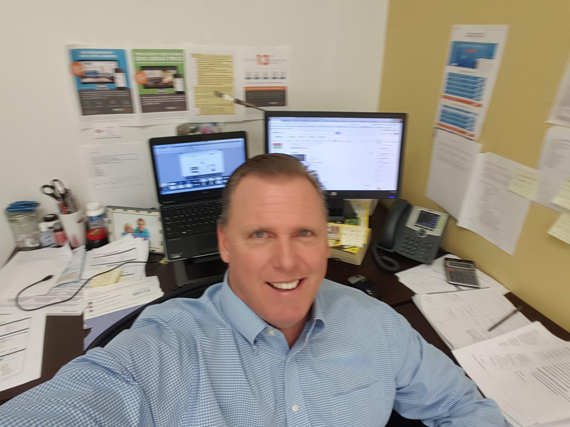 Brian Brown pictured at a desk with two computer screens and marketing materials