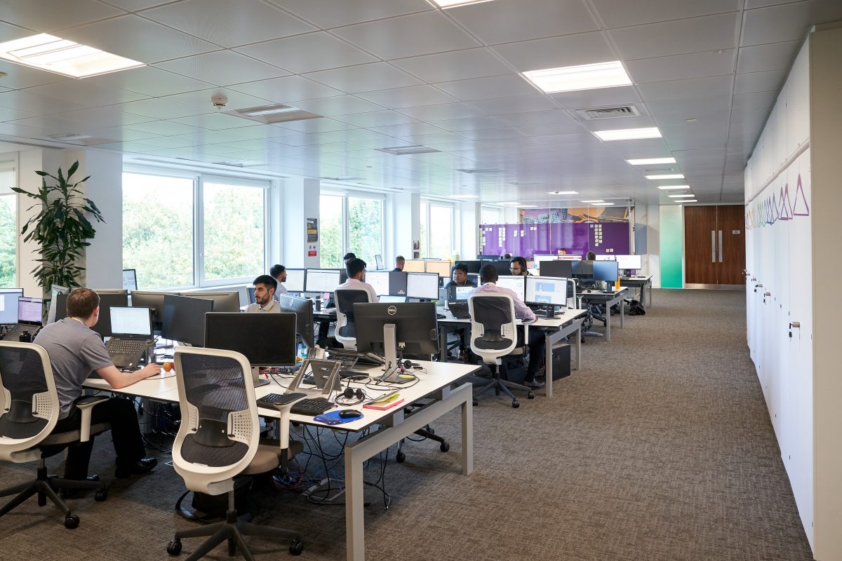 People working at rows of monitors in an open-plan Phoebus office