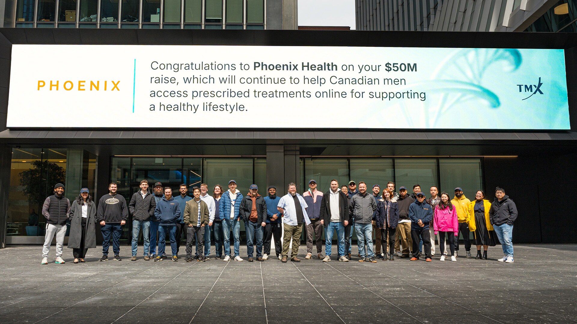 Phoenix and Raven team members standing together beneath a billboard celebrating the company's financing