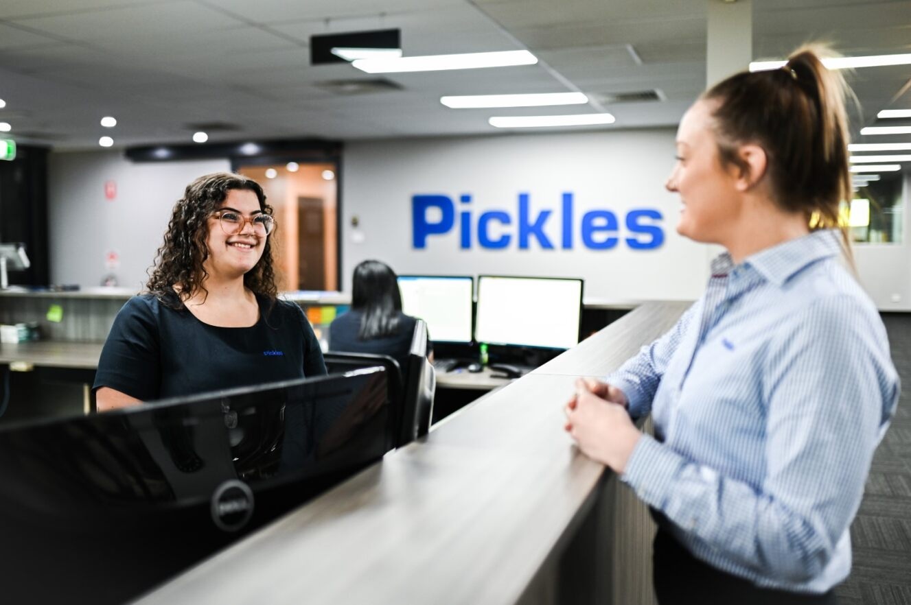 Pickles staff talking across an office reception desk