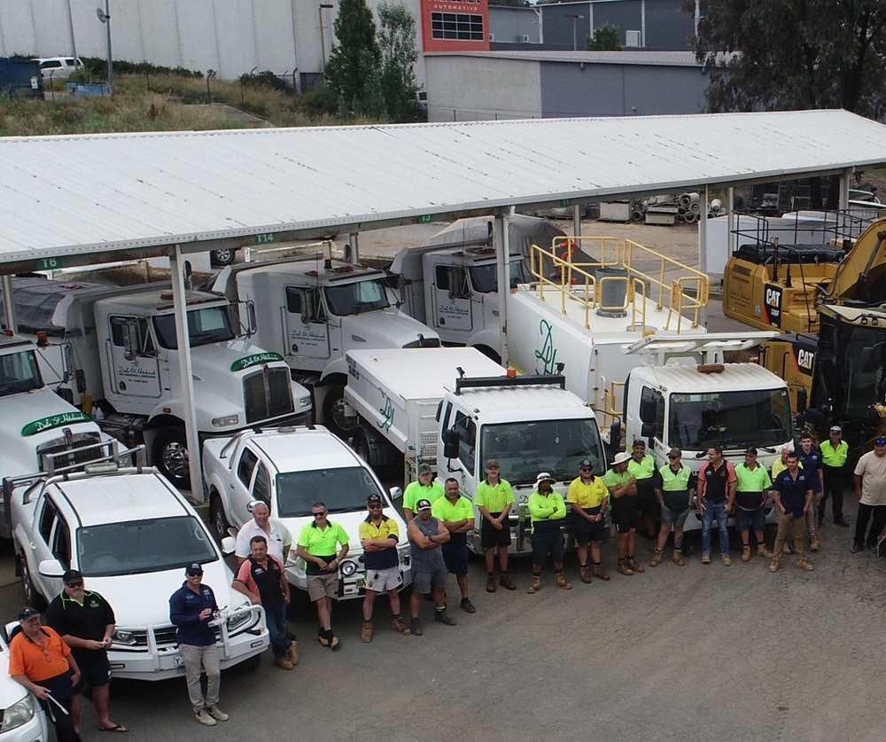 Dale and Hitchcock staff standing beside their trucks and earthmoving equipment