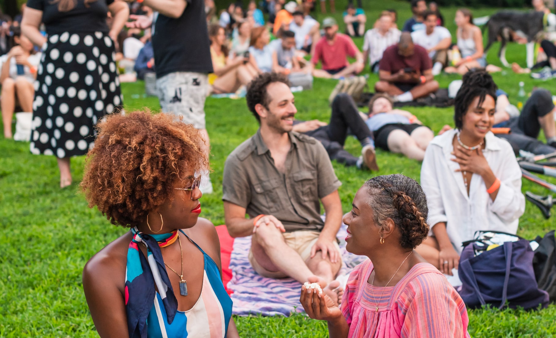 People talk together on blankets after an outdoor community screening