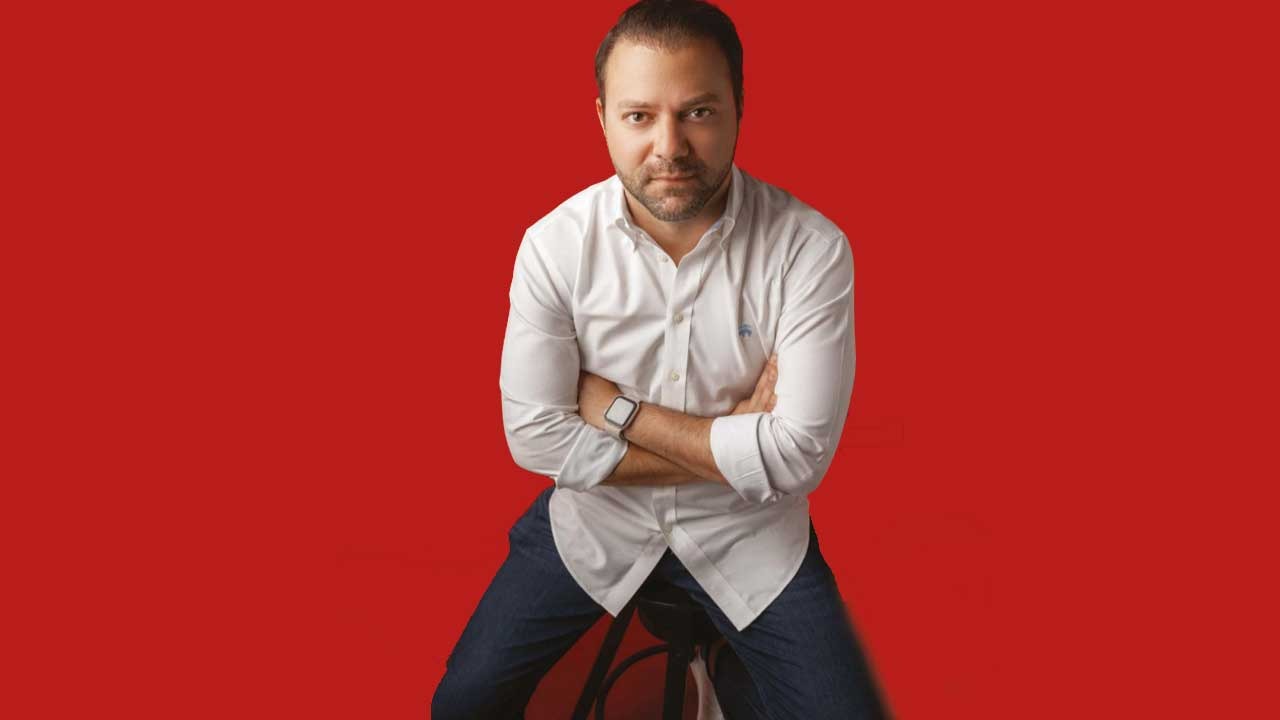 Piero Nunez del Risco seated in a white shirt against a red background