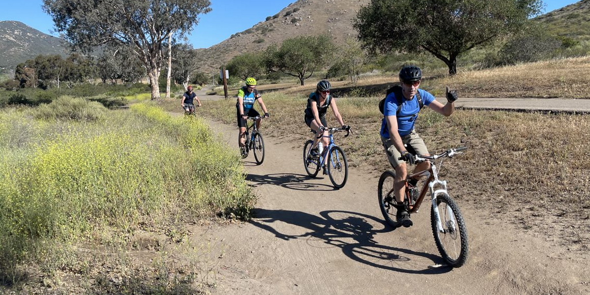 Four members of the Pleno team cycling on a hillside trail