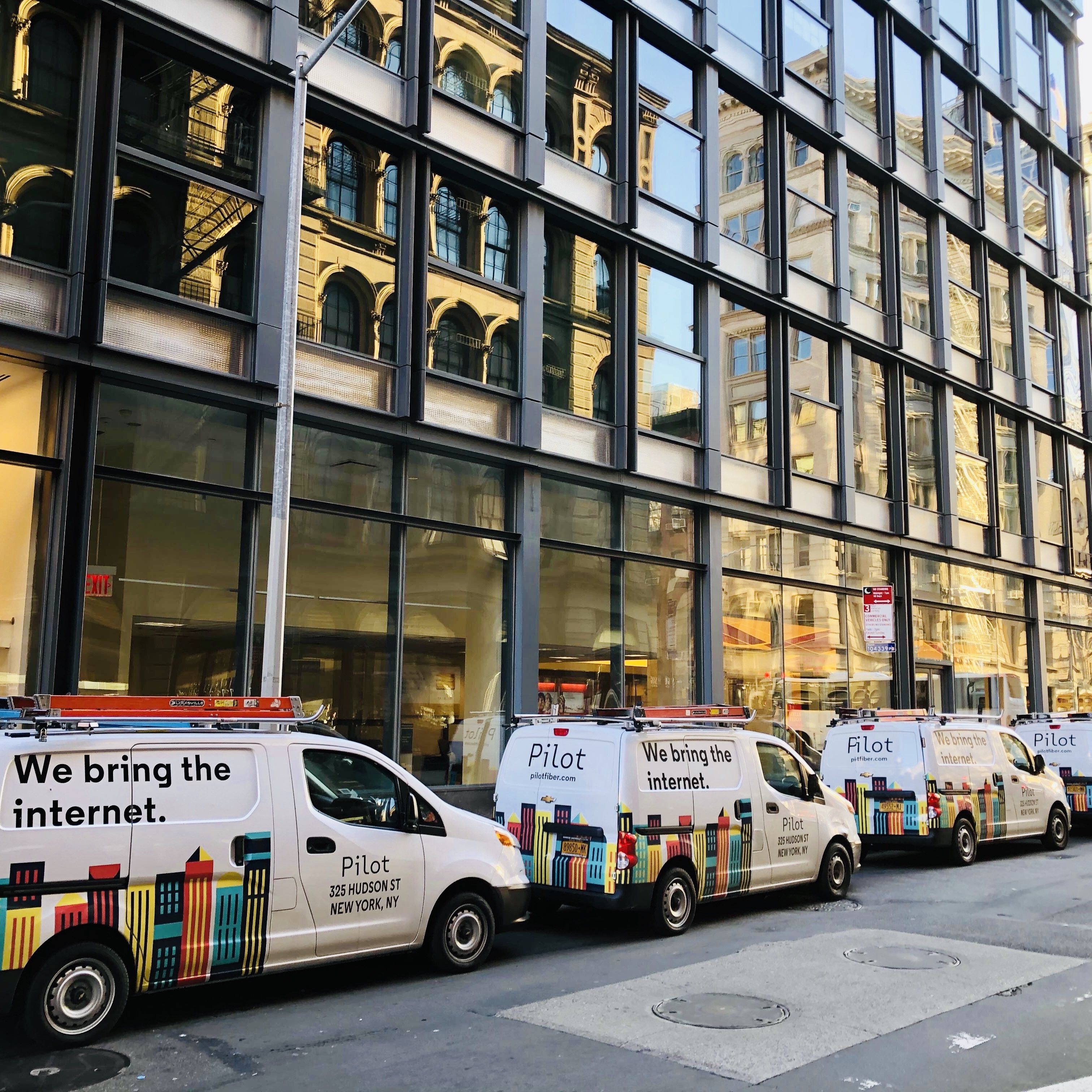 Pilot Fiber service vans parked outside a New York commercial building