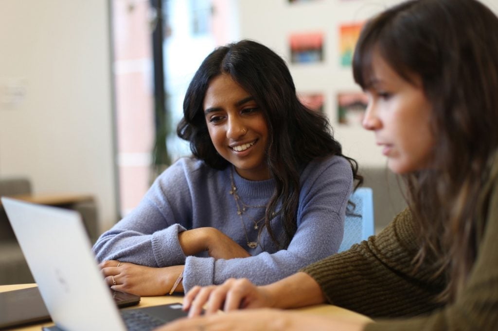 Two people collaborating at a laptop in an image used on Pinion Newswire's About page