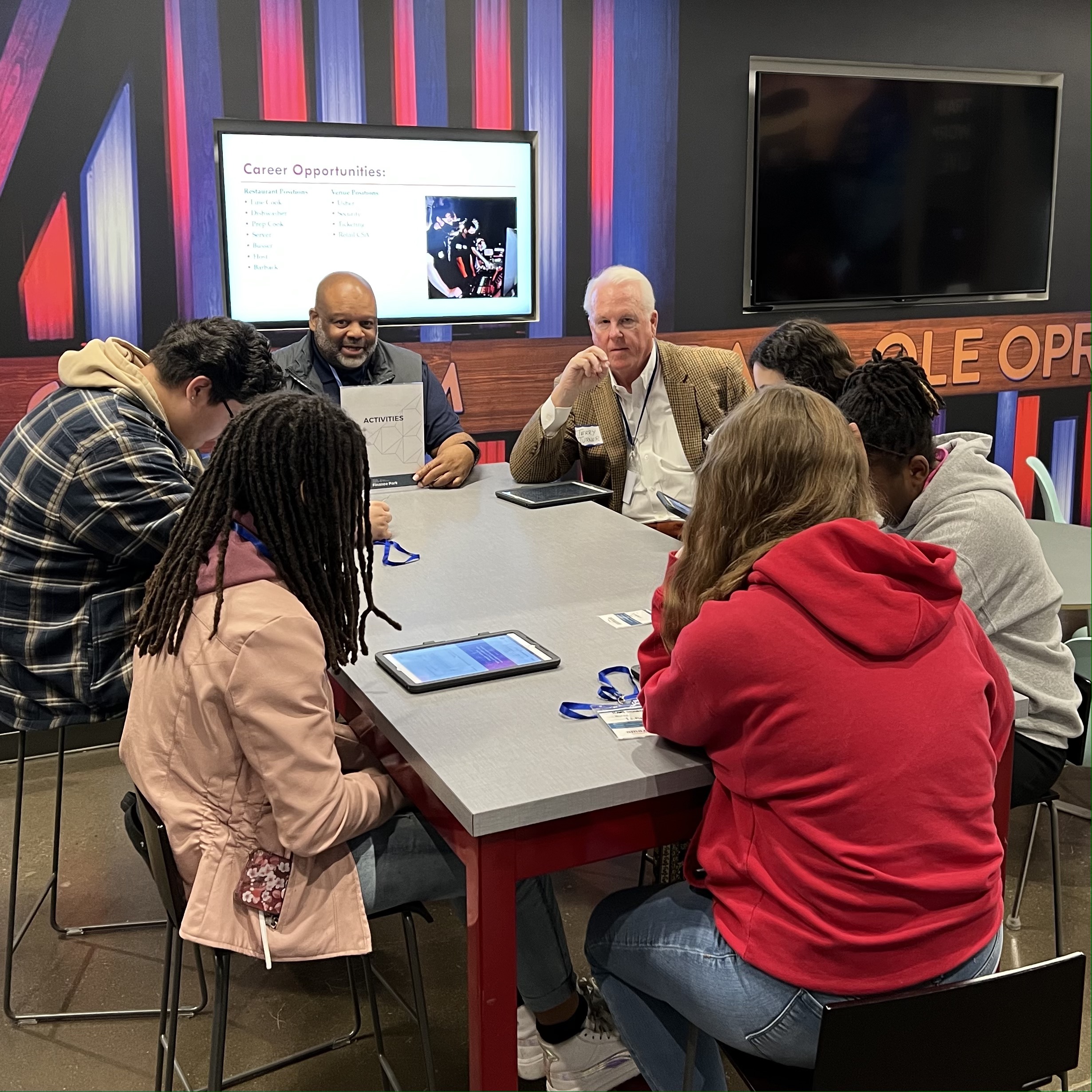 Pinnacle cofounder Terry Turner sitting with students around a table during a budgeting session