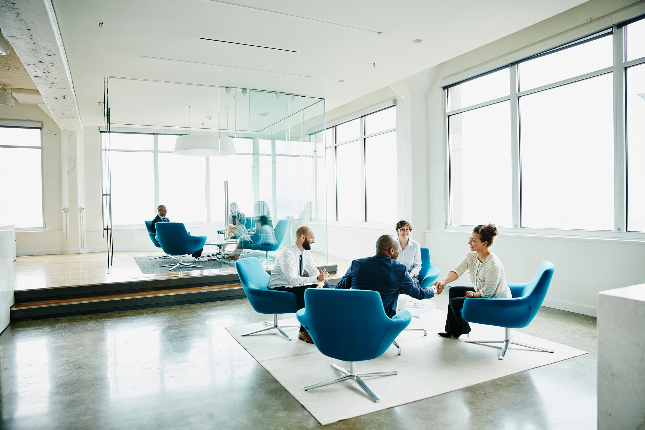 People meeting in a bright office with blue chairs, from Piper Sandler’s press image library