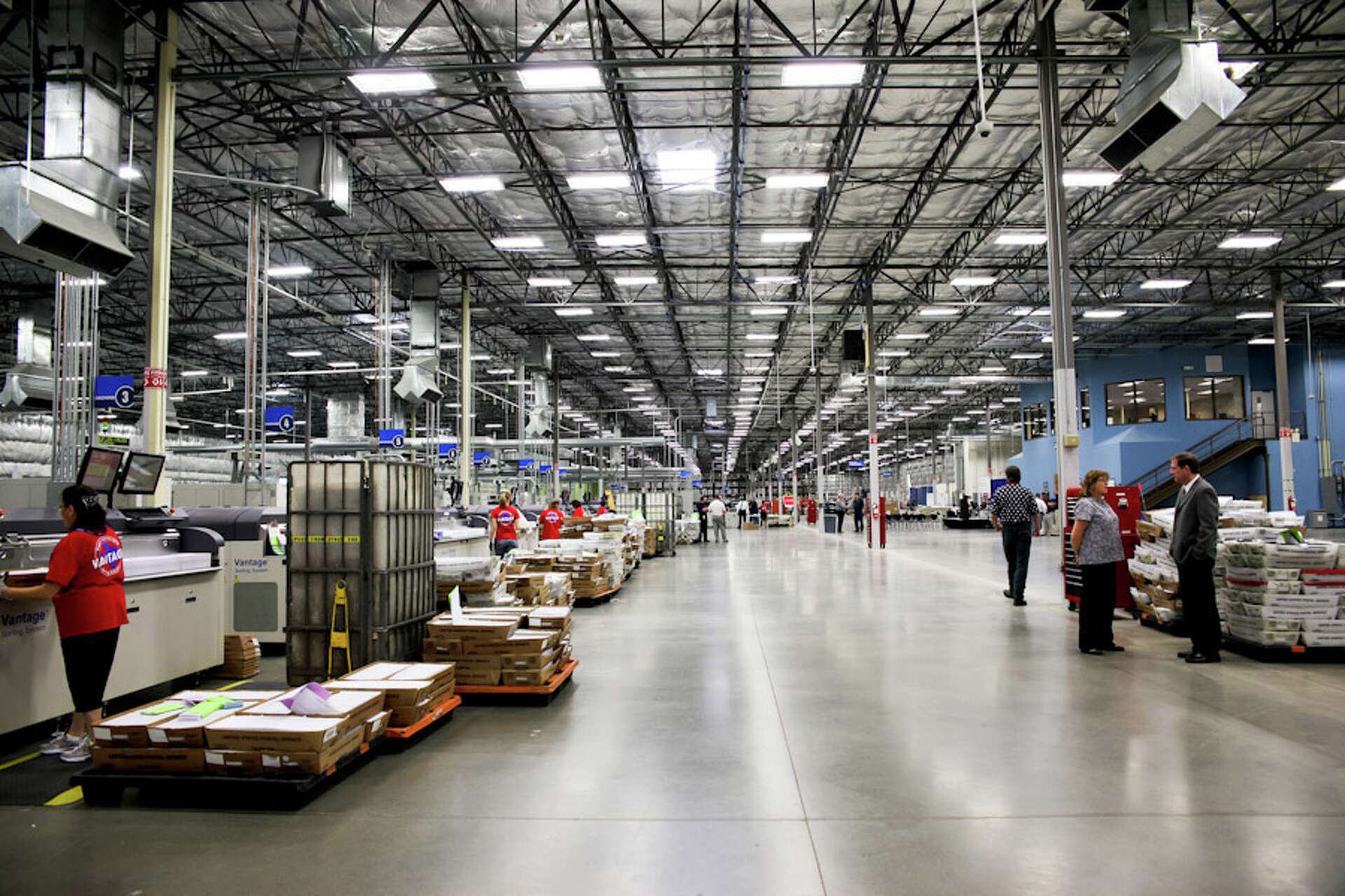 Workers and rows of sorting equipment inside Pitney Bowes’s Grand Prairie mail presorting facility