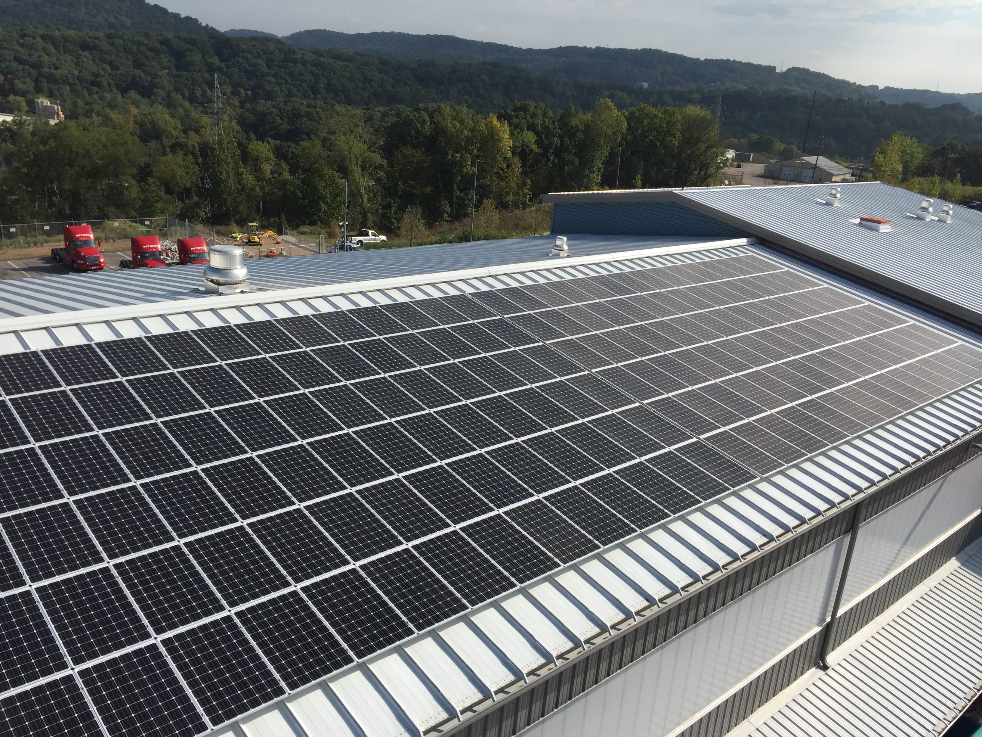 Solar panels on a PITT OHIO terminal roof with red trucks in the background