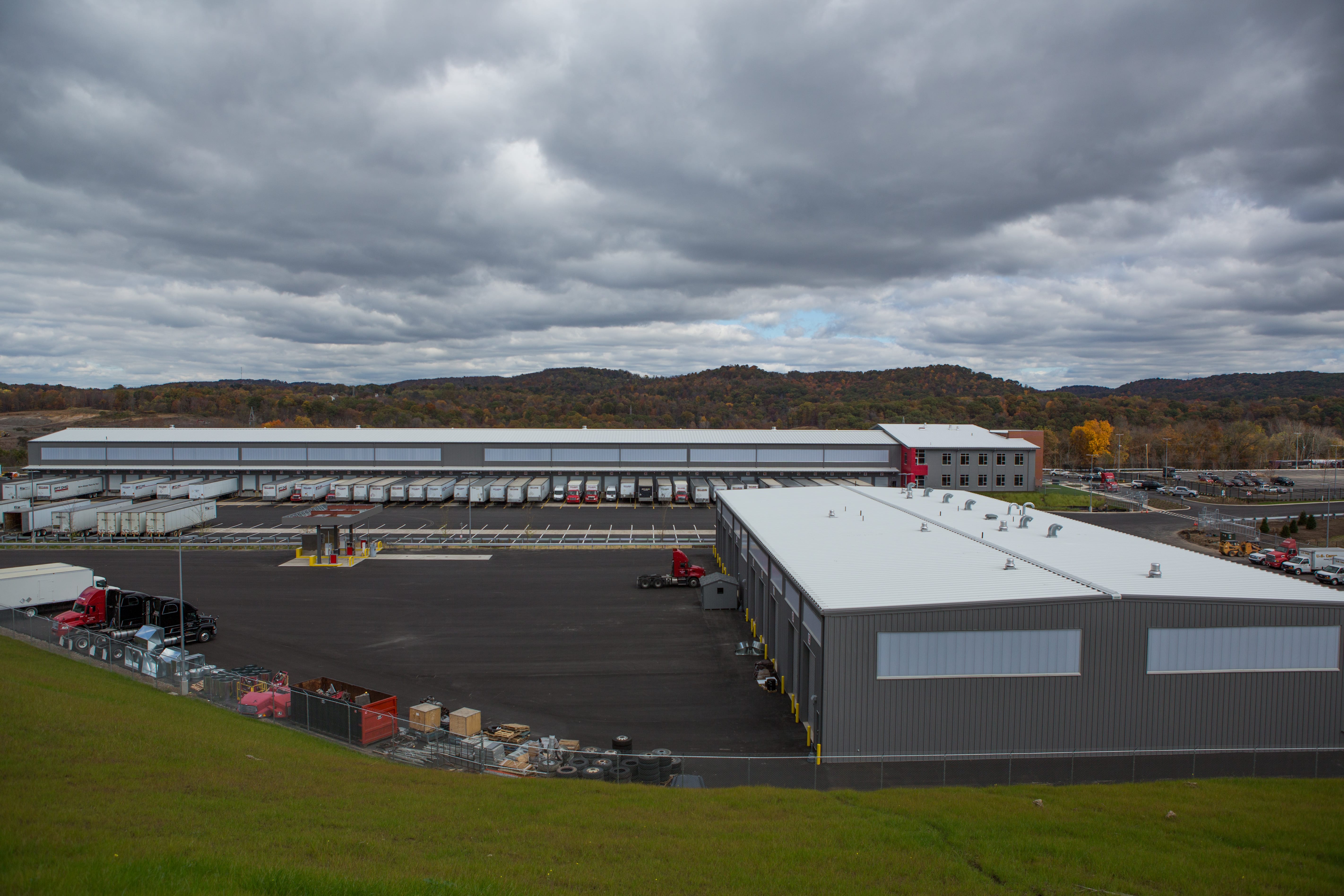 PITT OHIO terminal with rows of trailers, red trucks, and wooded hills