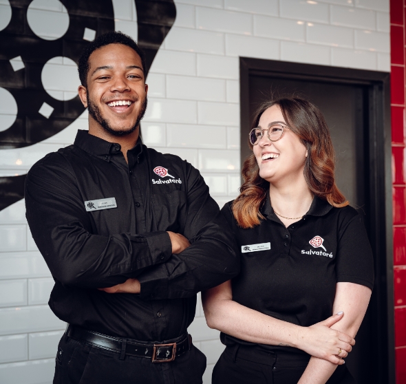 Two smiling Pizza Salvatoré restaurant team members in black uniforms