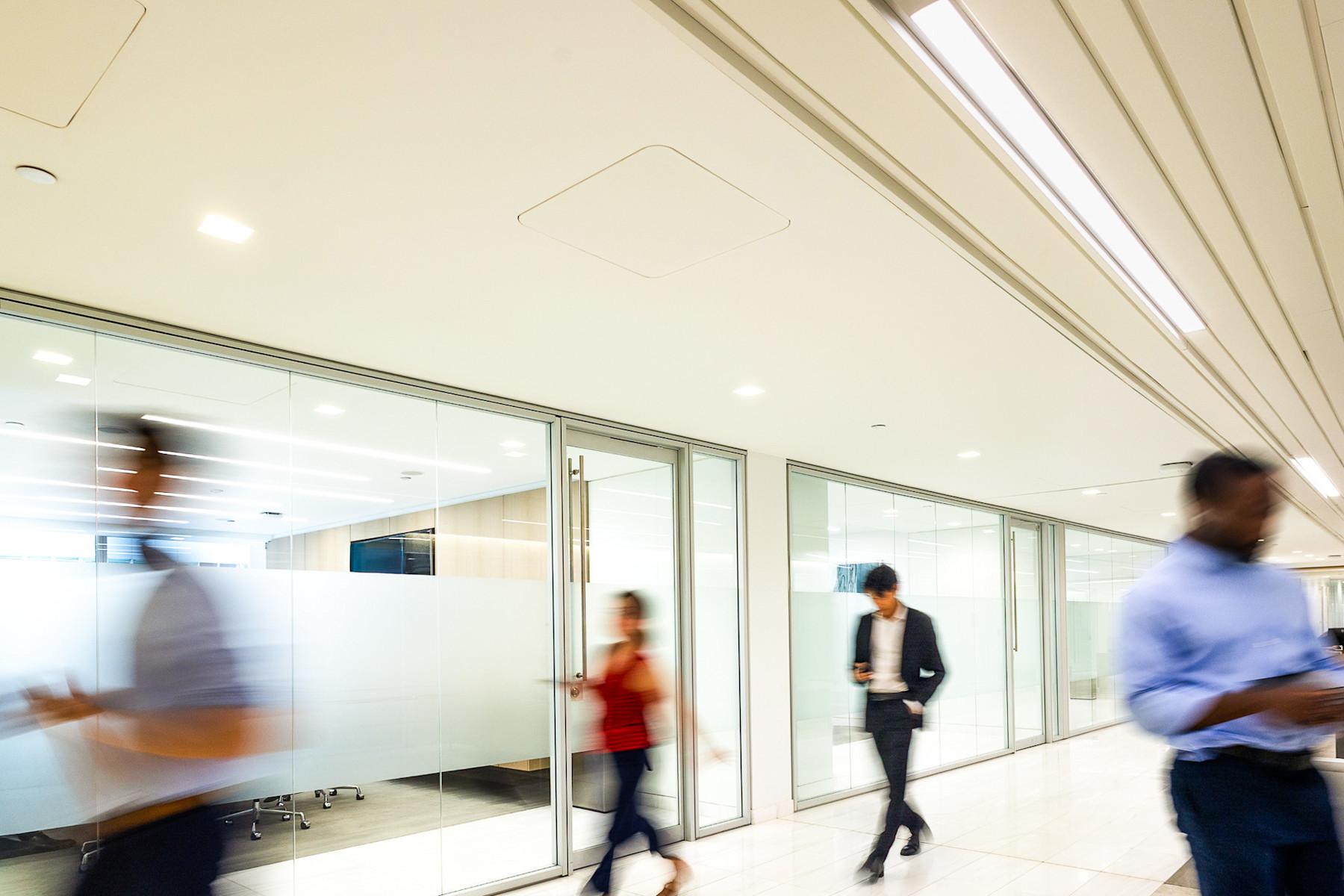 People walking through a bright, glass-partitioned office, in a photograph published by PJT Partners