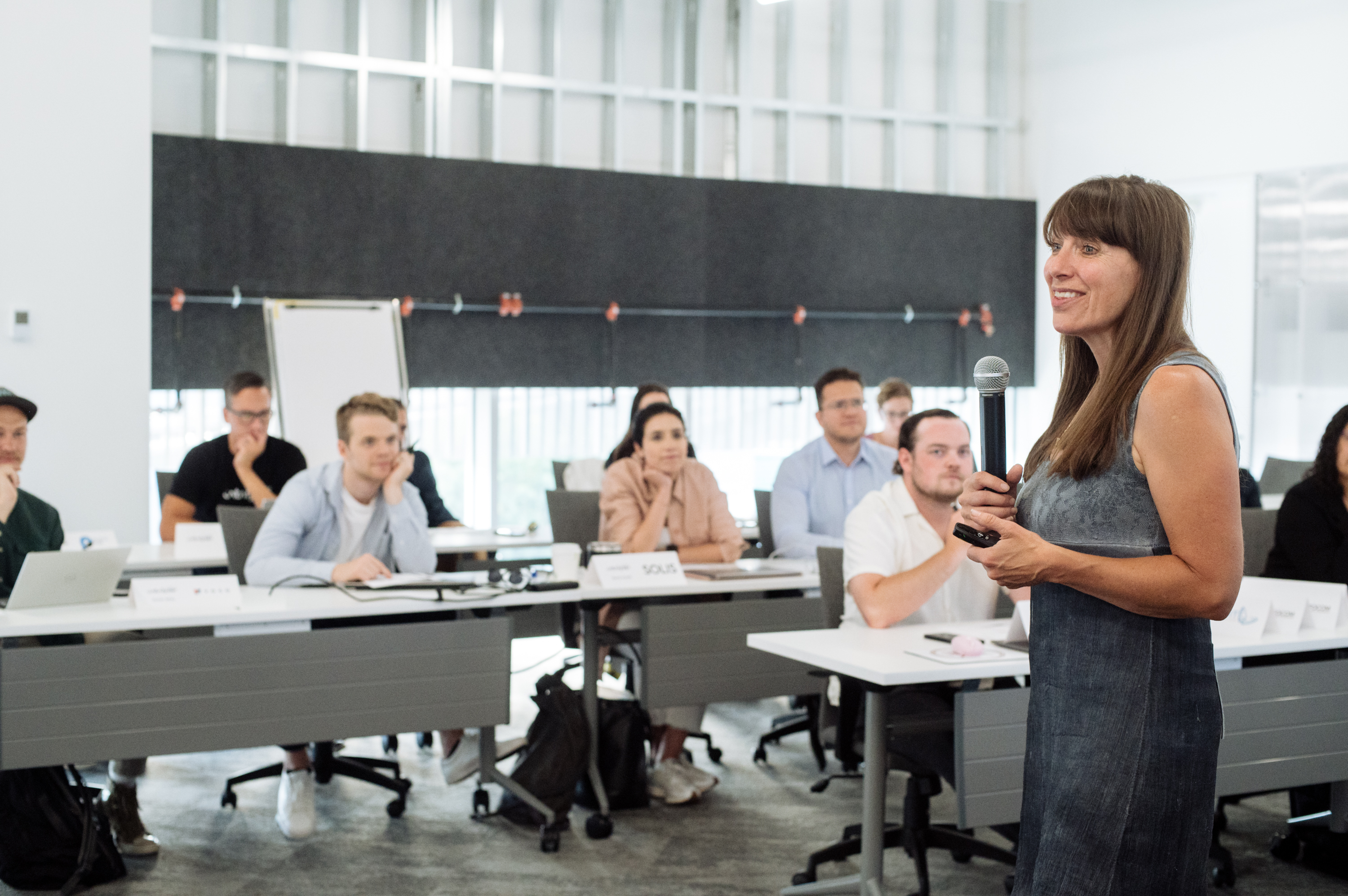 A facilitator with a microphone leads a classroom session attended by entrepreneurs