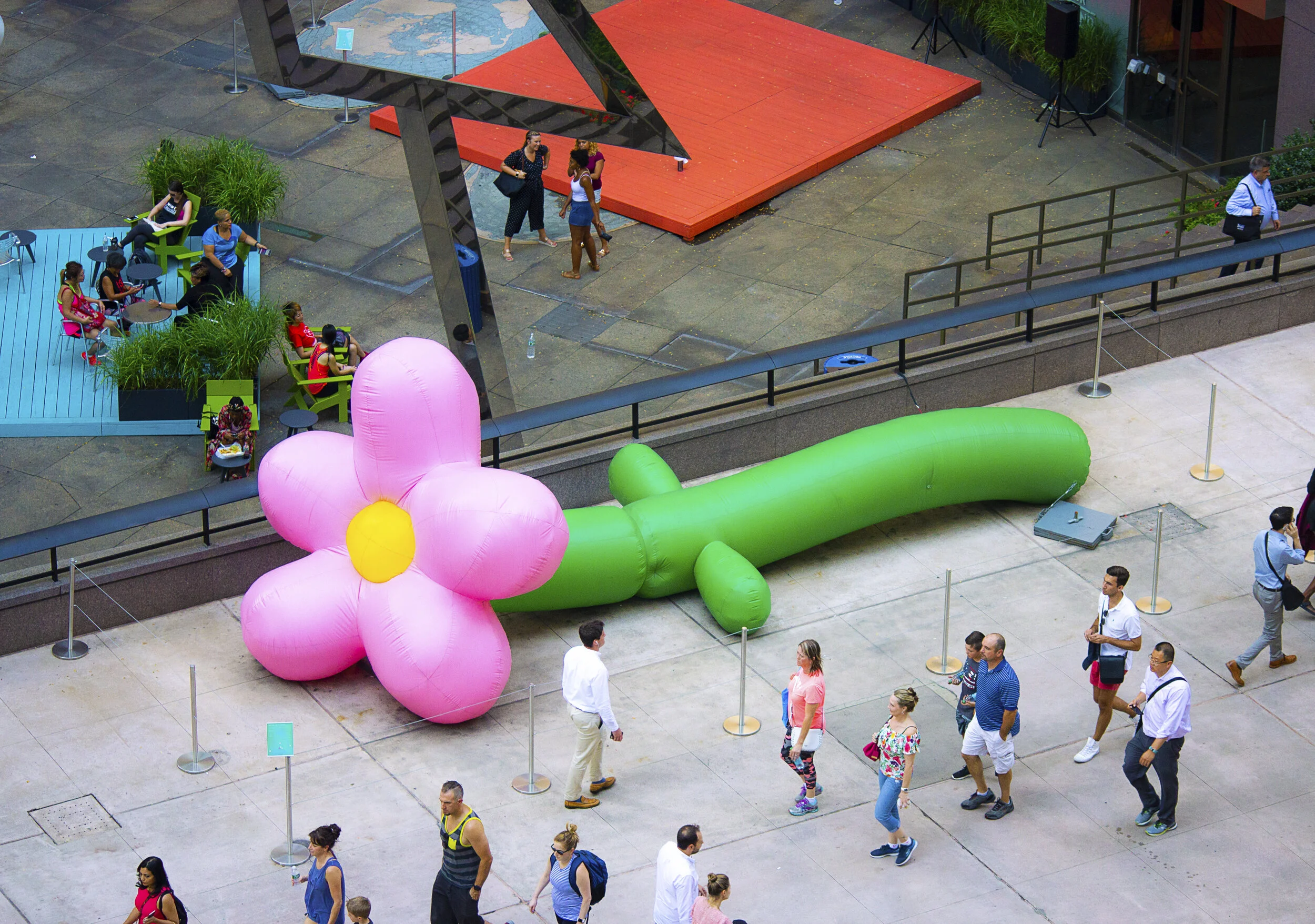 An enormous pink inflatable flower lies across a Manhattan plaza as pedestrians pass