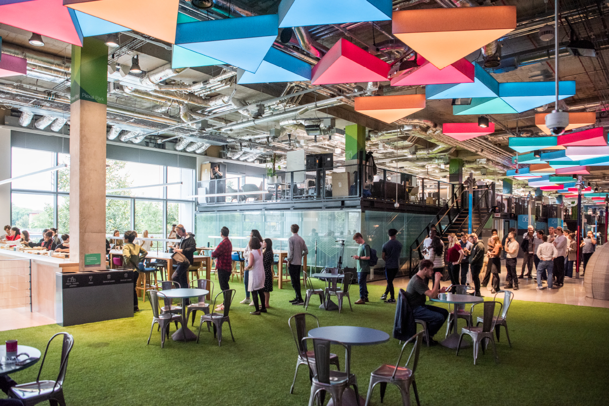 People meeting beneath colourful ceiling panels in Plexal’s Stratford workspace