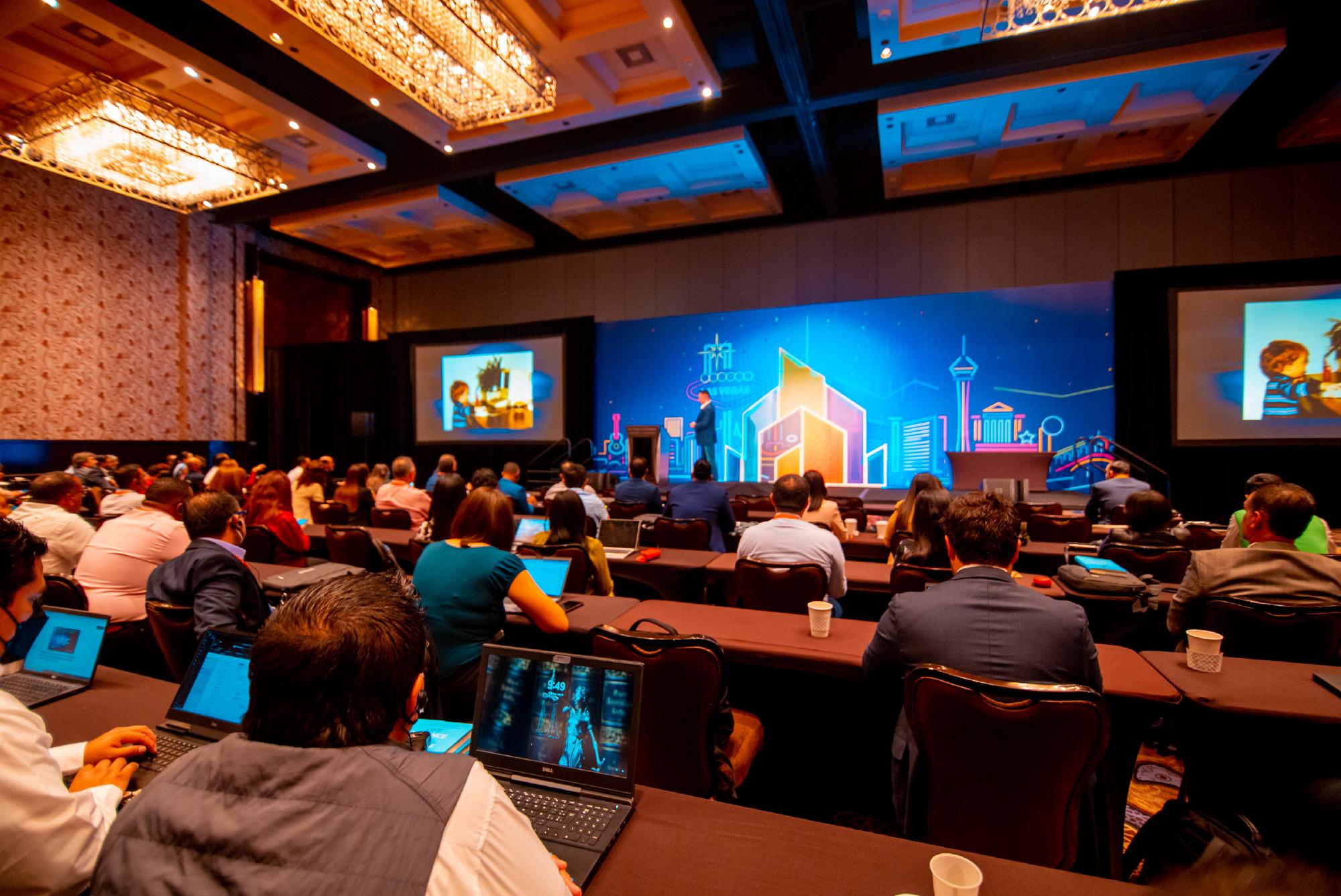 Attendees with laptops listening to a presentation at a PLUS TI conference