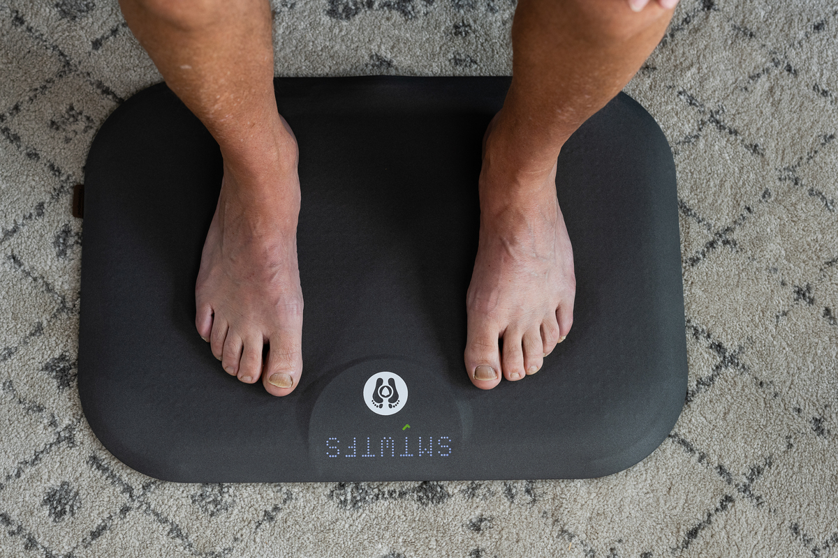 A patient standing barefoot on the Podimetrics SmartMat