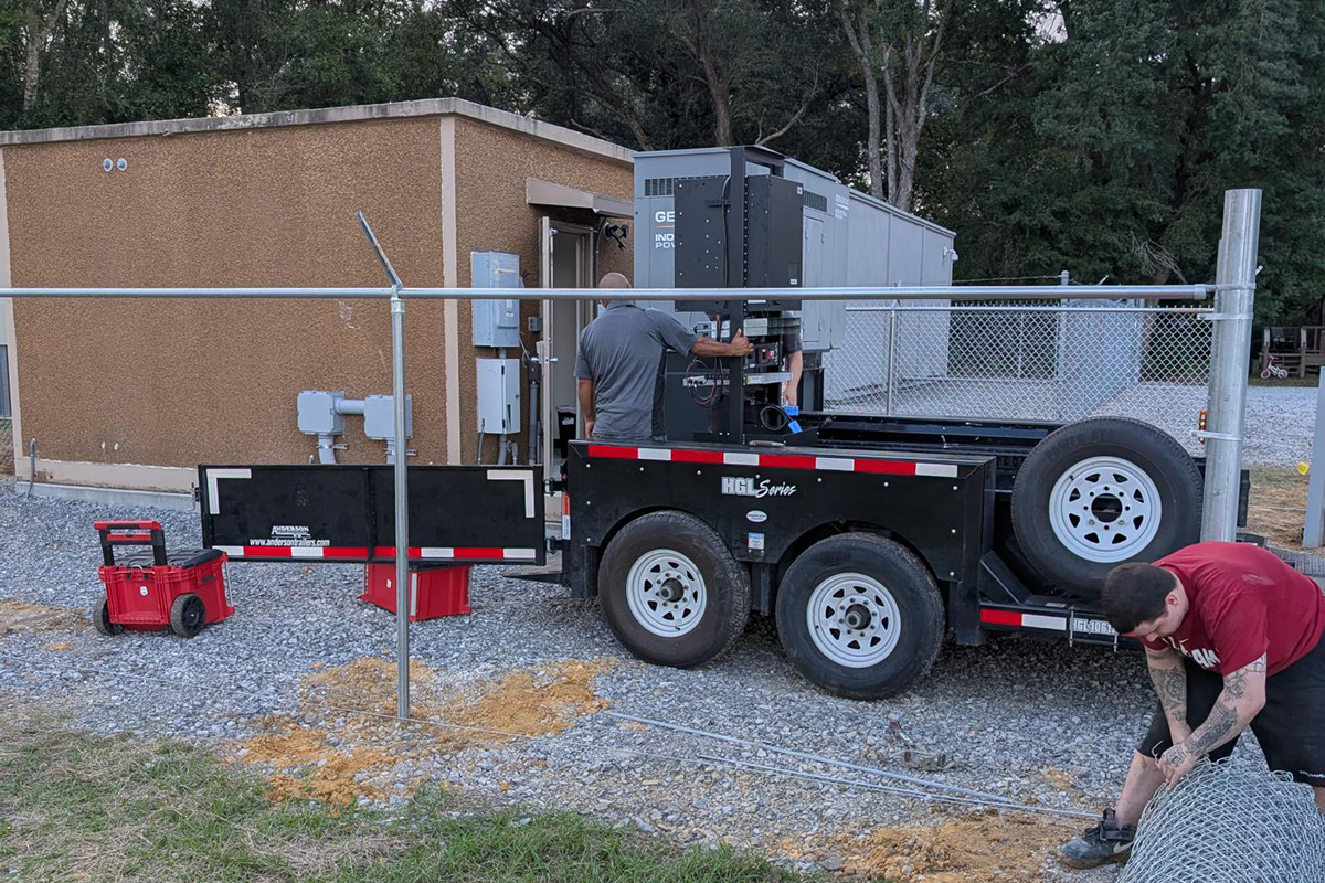 Workers install equipment beside a building at a Foley network site.