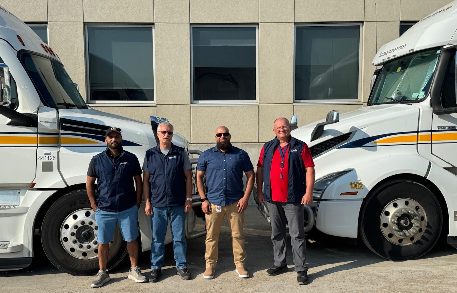 Polaris highway drivers Tajinder Pal Singh, Piotr Tobiasz and Volodymyr Barulin with director of operations Mo Baki between company trucks