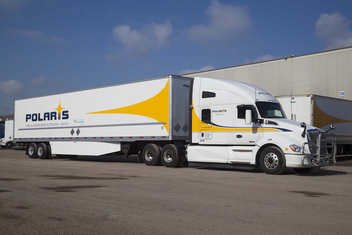 A Polaris tractor and branded freight trailer parked outside a warehouse