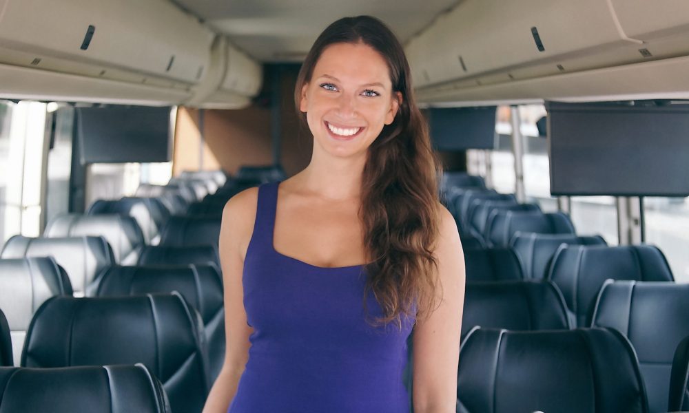 Polina Raygorodskaya standing inside a bus, surrounded by rows of passenger seats