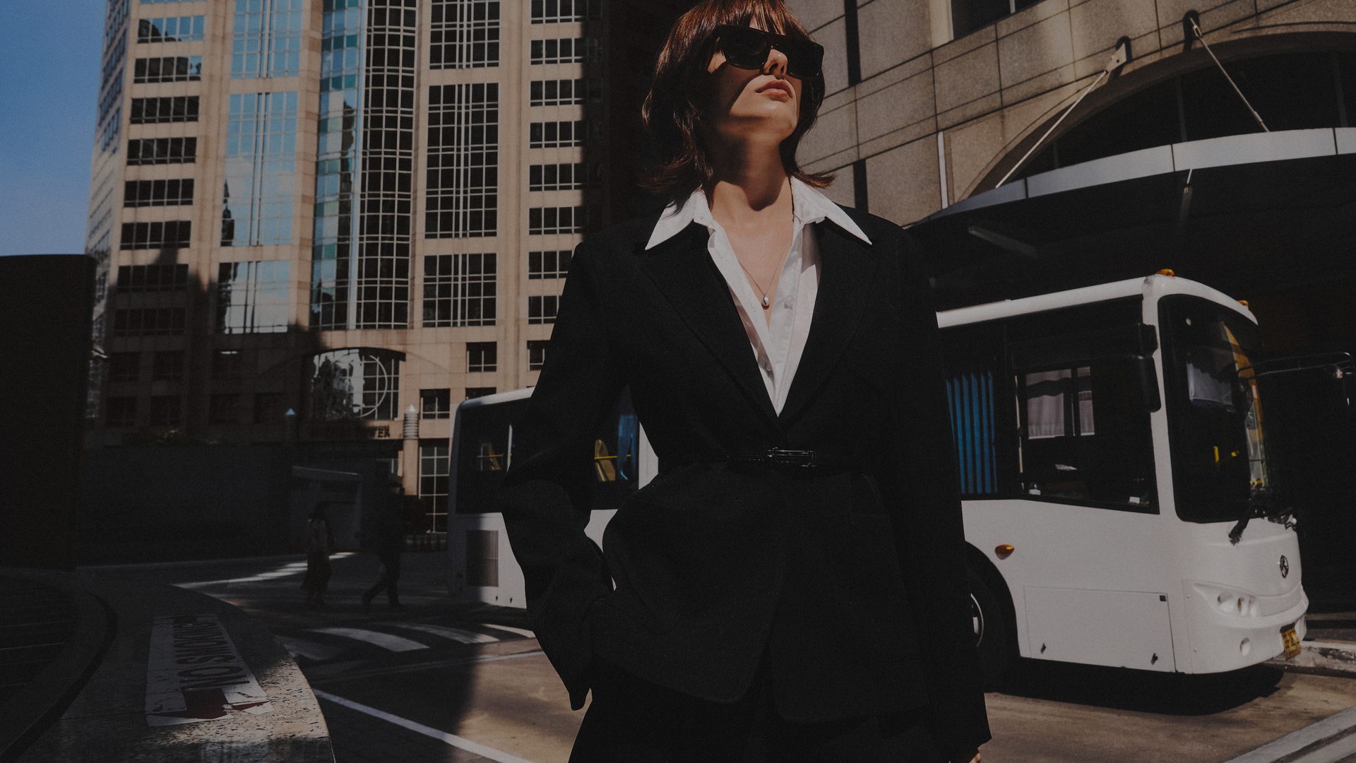Pomelo fashion photograph showing a woman in a black tailored jacket and white shirt on a city street