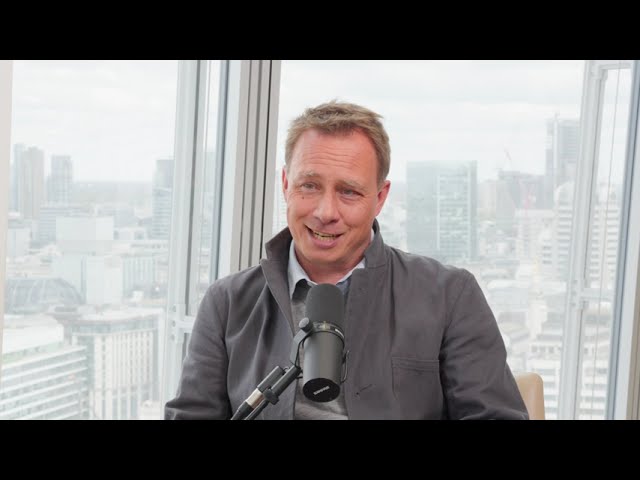 Pontus Noren speaking into a microphone during his Arma Partners interview, with London visible behind him