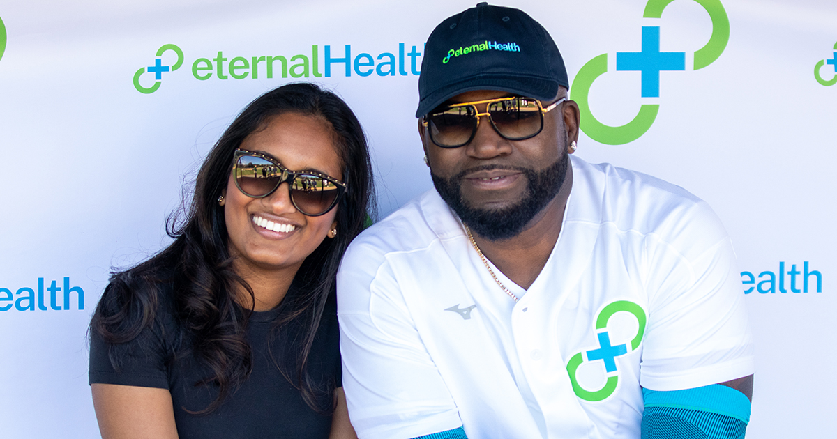 Pooja Ika and David Ortiz smiling together in front of an eternalHealth backdrop