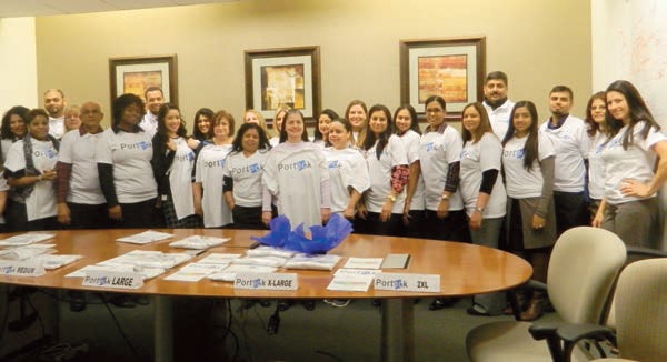 Porteck employees gathered around a conference table wearing matching company shirts