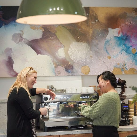 Two people using the coffee machine in PorterShed’s communal space