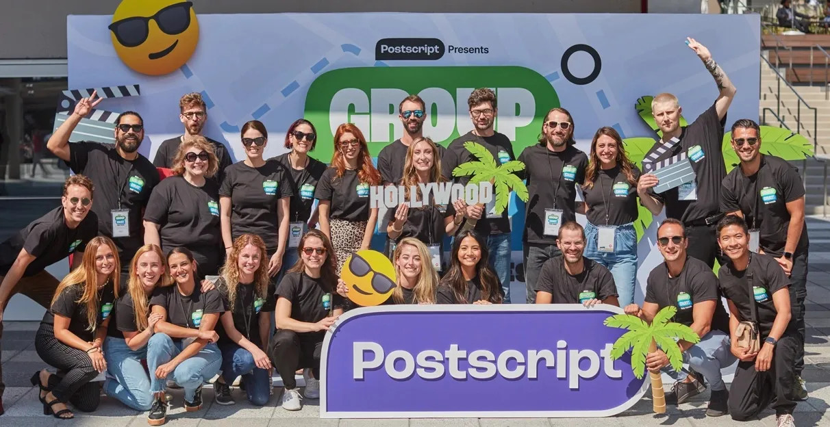 Postscript team members posing together with film props and a purple Postscript sign