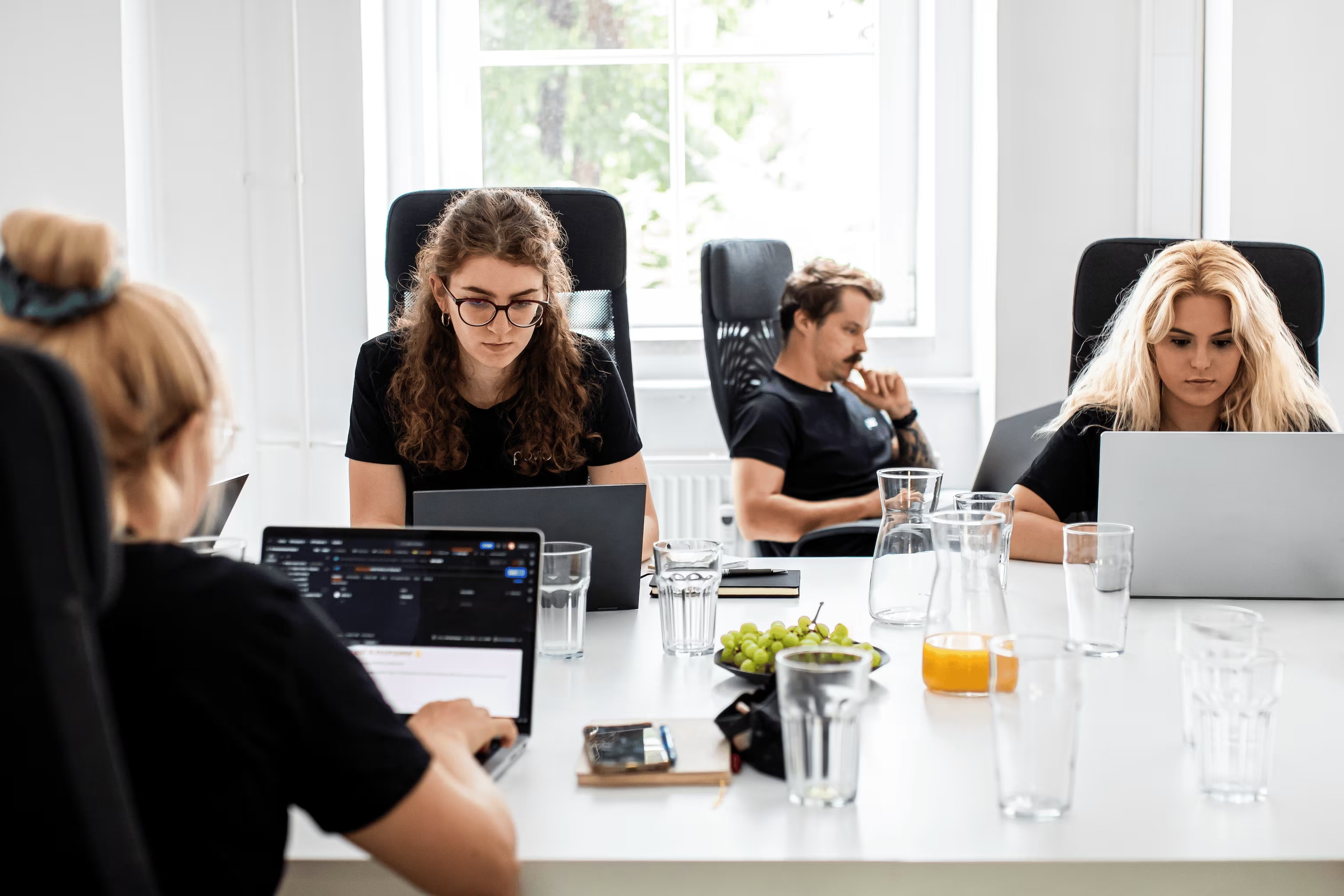 Four Povio colleagues working together on laptops around a white table