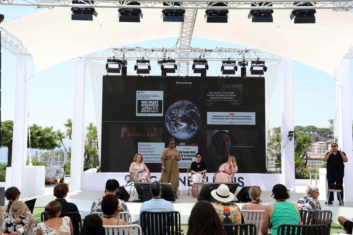 A panel discussion at Cannes Lions with an audience seated beneath a white canopy