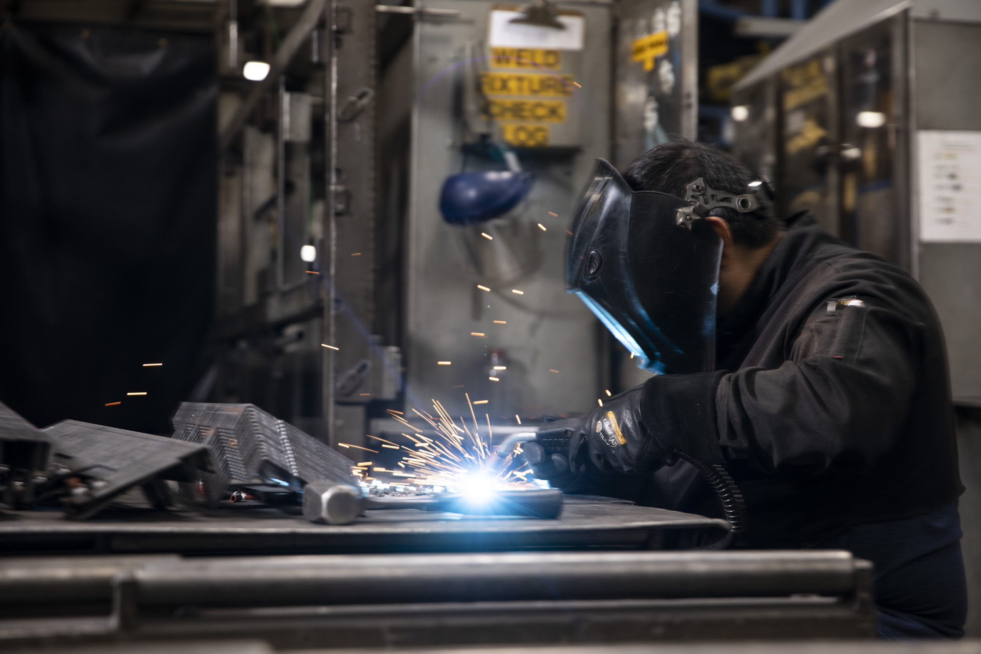 A Powell worker in protective equipment welds a metal assembly