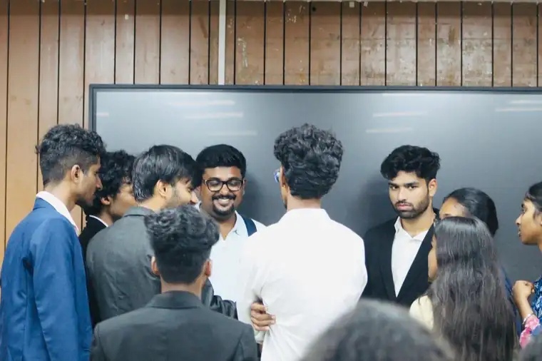 Prady smiling while talking with a group of students after a campus session